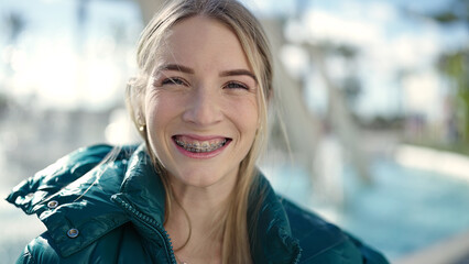 Young blonde woman smiling confident showing braces at park - obrazy, fototapety, plakaty