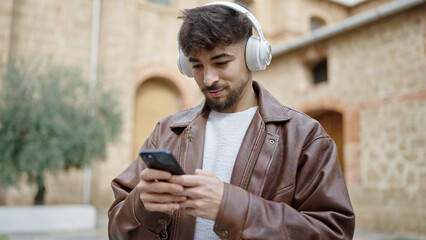 Young arab man listening to music with relaxed expression at street