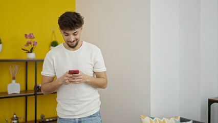 Young arab man using smartphone standing at home