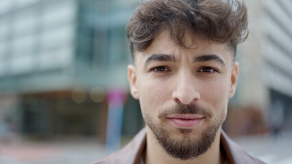 Young arab man standing with serious expression at street