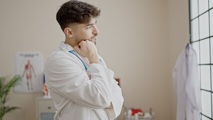 Young arab man doctor standing with arms crossed gesture and relaxed expression at clinic