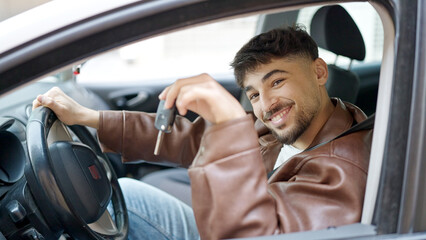 Young arab man smiling confident holding key of new car at street