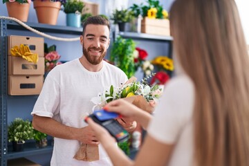Man and woman customer buying bouquet of flower by credit card at flower shop