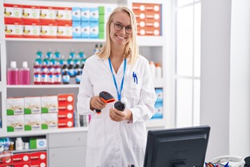 Young blonde woman pharmacist scanning medication bottle at pharmacy