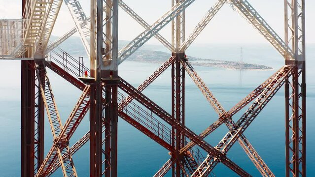Aerial view of high voltage big pylon structure near the ocean