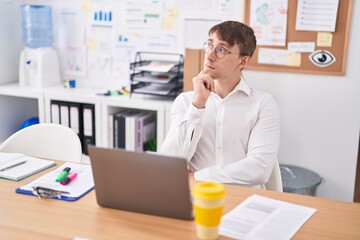 Young caucasian man business worker using laptop with doubt expression at office