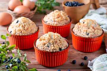 Blueberry muffins baked with fresh blueberries on wooden table with fresh mint