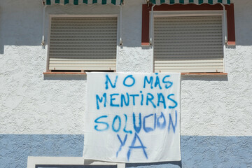 Banner on building wall with spanish words No mas mentiras, solucion YA. People protest,...
