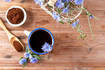 Healthy chicory drink in cup decorated chicory flowers on a table. Herbal beverage, coffee substitute. Close up. Copy space. - obrazy, fototapety, plakaty