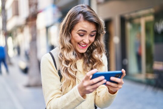 Young woman tourist smiling confident watching video on smartphone at street