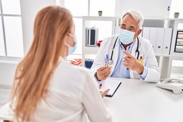Fototapeta premium Middle age man and woman doctor and patient wearing medical mask having consultation at clinic