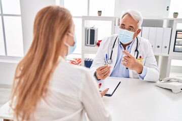Middle age man and woman doctor and patient wearing medical mask having consultation at clinic