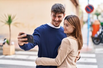 Mand and woman couple hugging each other make selfie by smartphone at street