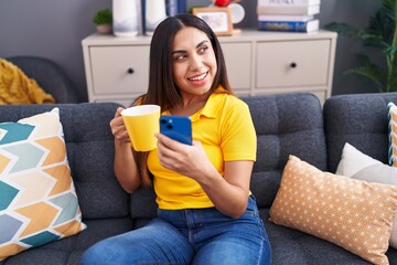 Young beautiful arab woman using smartphone drinking coffee at home