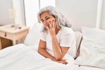 Middle age woman stressed sitting on bed at bedroom