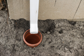 House gutter. Rainwater drainage system concept. White pipe for rainwater from roof on building and drain pipe in ground - obrazy, fototapety, plakaty