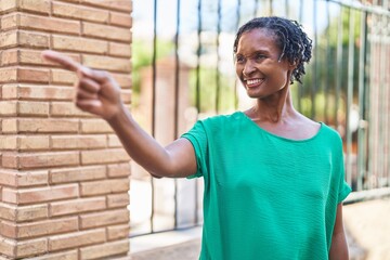 Middle age african american woman smiling confident pointing with finger at street