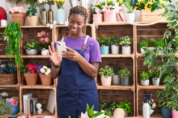 African american woman florist smiling confident using smartphone at florist