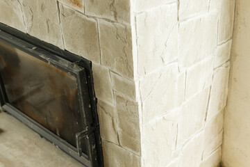 Fireplace close up in unfinished living room, home renovation concept. Decorating fireplace with natural stone and wooden mantel.