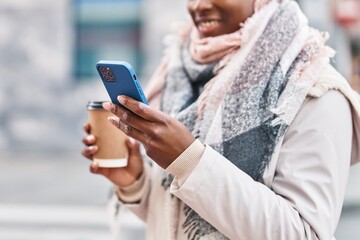 African american woman using smartphone drinking coffee at street