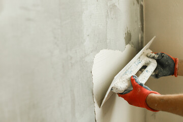 Worker plastering walls with gypsum plaster and spatula . Construction of house and home renovation concept. Close up of stucco and handyman hands with trowel