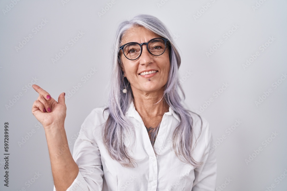 Wall mural middle age woman with tattoos wearing glasses standing over white background with a big smile on fac