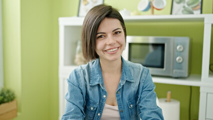 Young caucasian woman smiling confident sitting on table at home