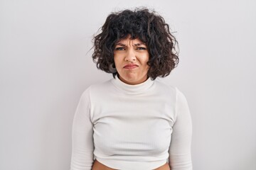 Hispanic woman with curly hair standing over isolated background depressed and worry for distress, crying angry and afraid. sad expression.