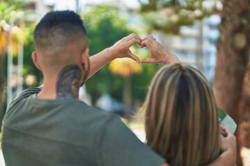 Man and woman mother and daugther doing heart gesture with hands at park