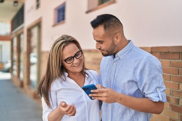 Fototapeta premium Man and woman mother and daugther using smartphone at street