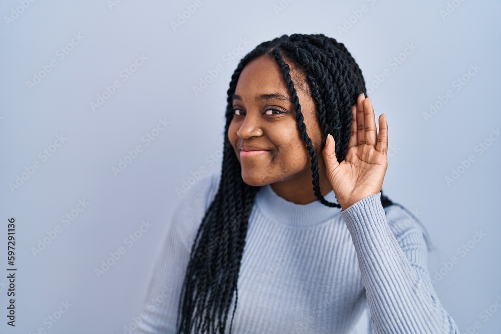 Poster African american woman standing over blue background smiling with hand over ear listening an hearing to rumor or gossip. deafness concept.