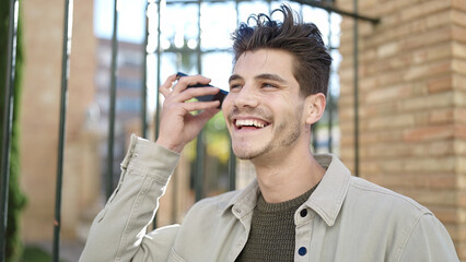 Young hispanic man smiling confident listening audio message by the smartphone at street