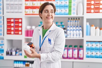 Young woman pharmacist scanning pills bottle at pharmacy