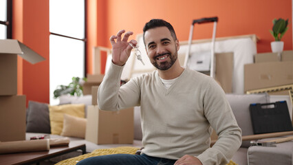 Young hispanic man smiling confident holding key at new home