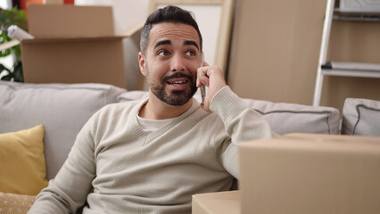 Young hispanic man smiling confident talking on smartphone at new home