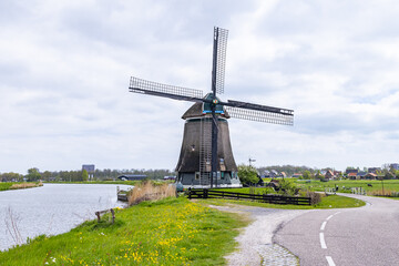 Traditional windmill on a Dutch canal and road.