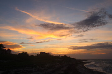 Espectacular atardecer con nubes en cielo dorado en la playa