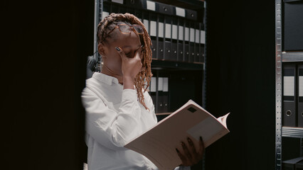 Detective inspector examining case files information in police archive room, reading witness...