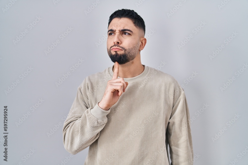 Poster Young handsome man standing over isolated background thinking concentrated about doubt with finger on chin and looking up wondering