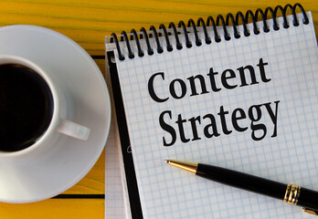 ?ONTENT STRATEGY - words on a white sheet on a yellow wooden background with a pen and a cup of coffee