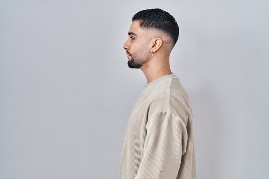 Young handsome man standing over isolated background looking to side, relax profile pose with natural face and confident smile.