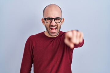 Naklejka premium Young bald man with beard standing over white background wearing glasses pointing displeased and frustrated to the camera, angry and furious with you