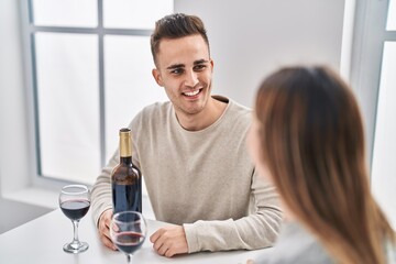 Man and woman couple drinking red wine sitting on table at home