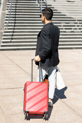 a man walking with a red suitcase, marching or arriving at his destination, traveling for business or work, vacation