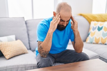 Fototapeta premium Young bald man stressed sitting on sofa at home