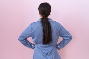 Young arab woman wearing blue pajama standing backwards looking away with arms on body