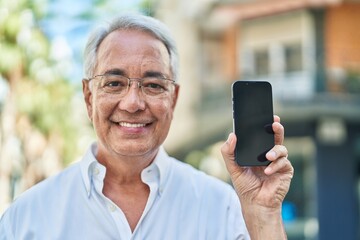 Obraz premium Middle age grey-haired man smiling confident showing screen smartphone at street