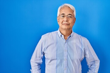 Obraz premium Hispanic senior man wearing glasses relaxed with serious expression on face. simple and natural looking at the camera.