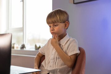 children, education and school concept - student boy with laptop computer learning at home