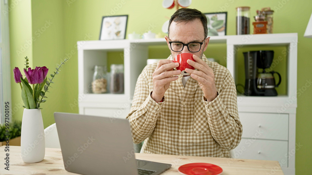 Sticker Middle age man using laptop drinking coffee at home